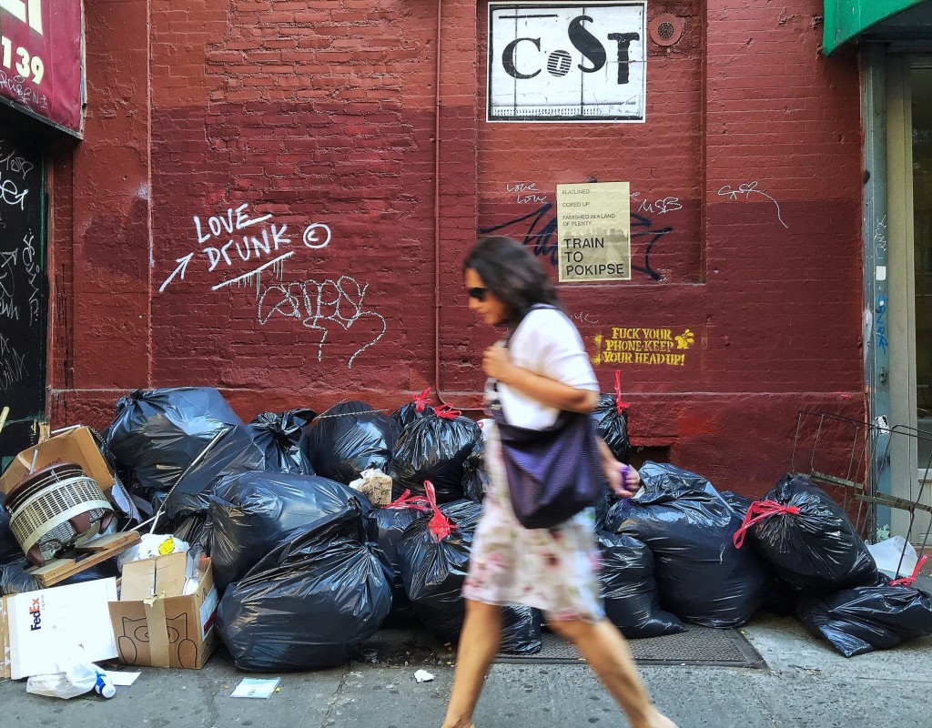 city woman walking past garbage in NYC